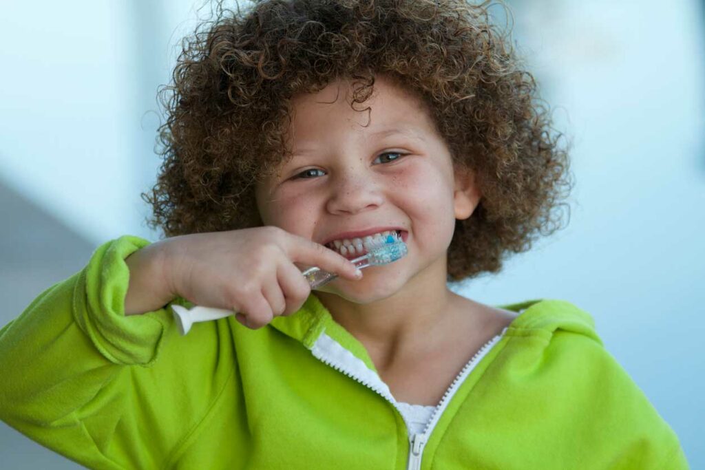 child smiling and brushing teeth