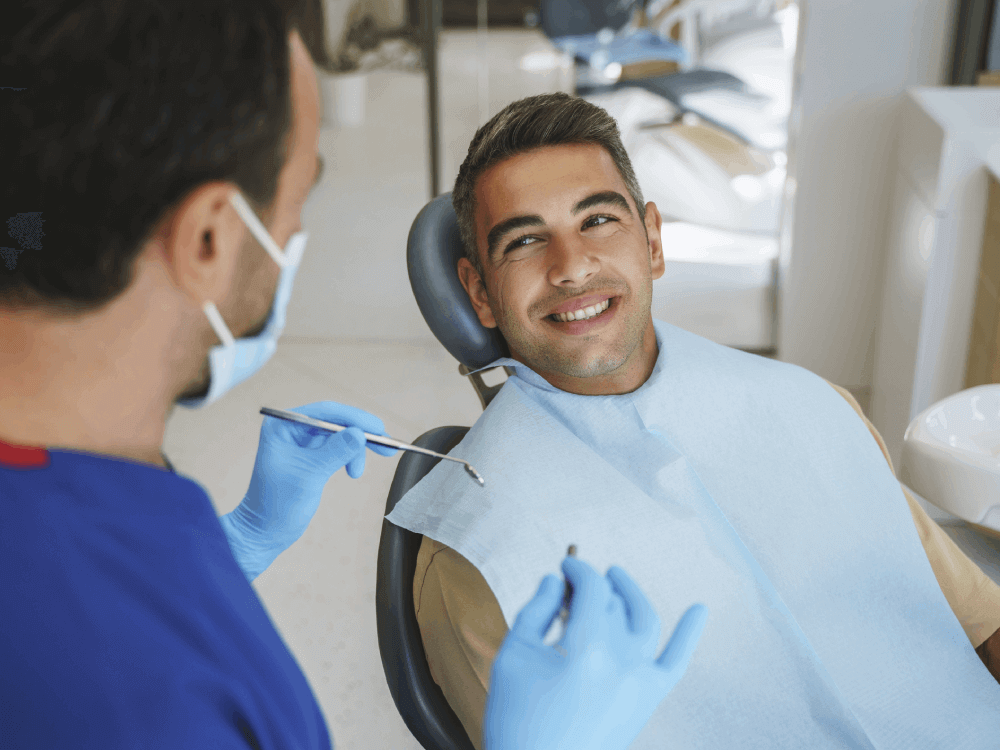 patient smiling at dentist as dentist holds dental tools