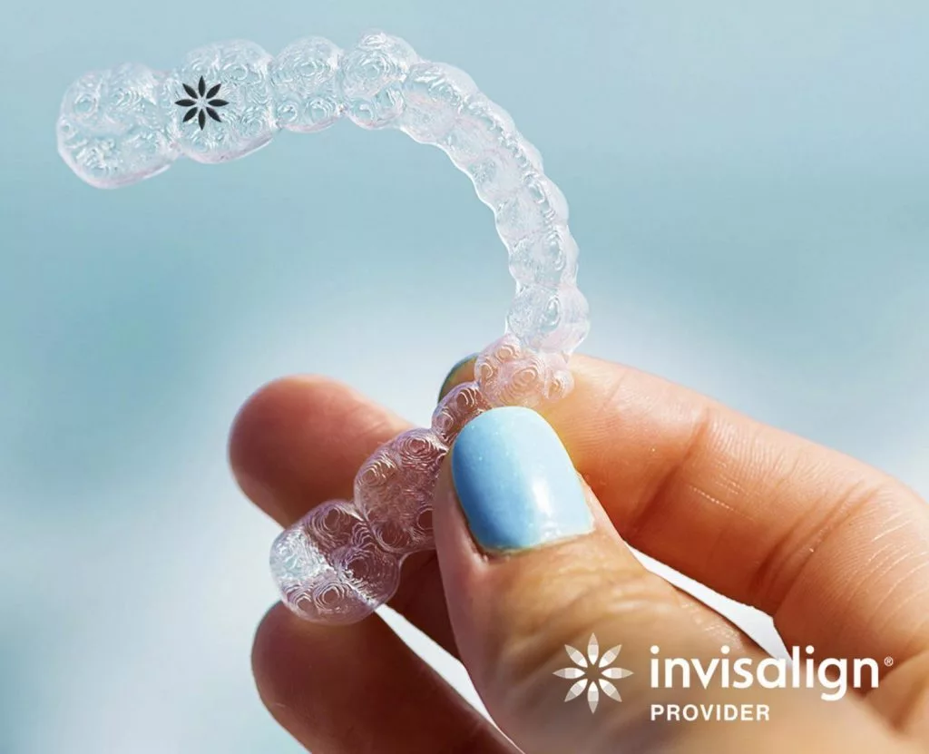 a hand holding an invisalign clear aligner